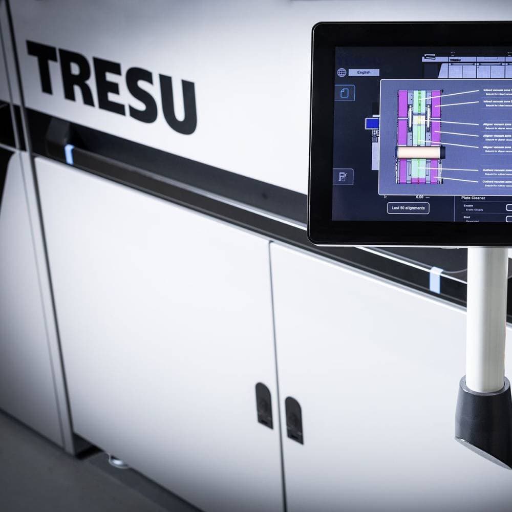 Control panel displaying colorful charts in front of a TRESU industrial printer.