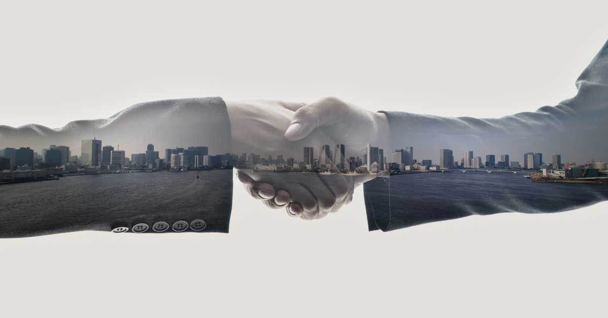 Håndtryk hvor by ses igennem transparente hænder og arme