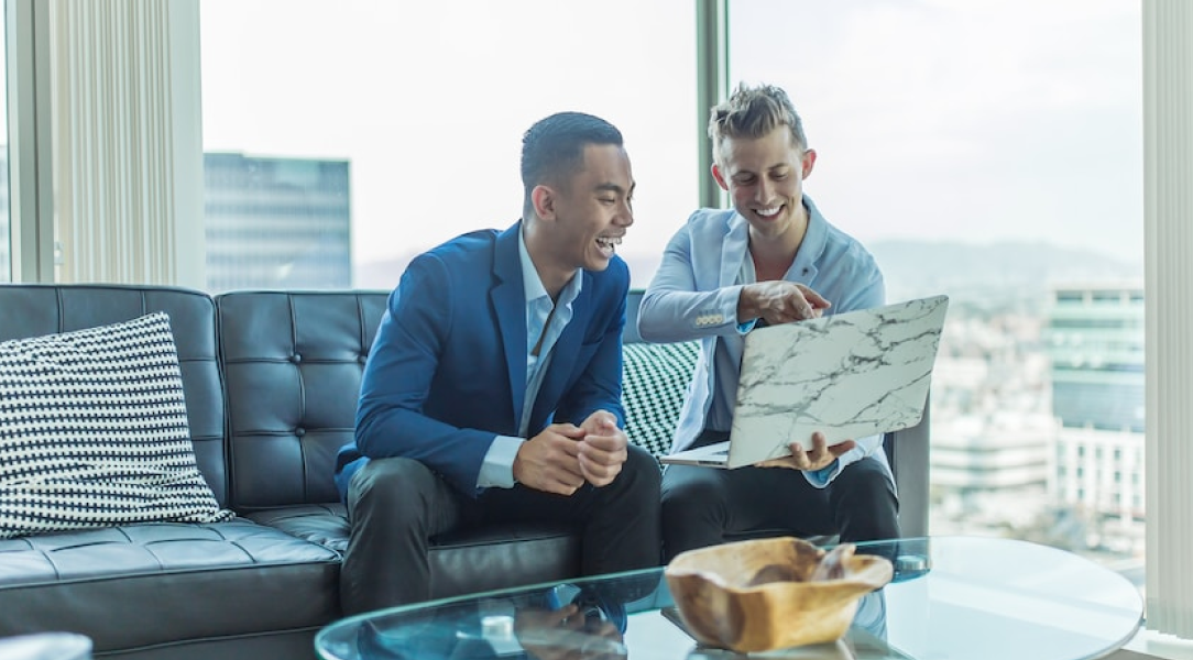 Two persons looking happily at laptop